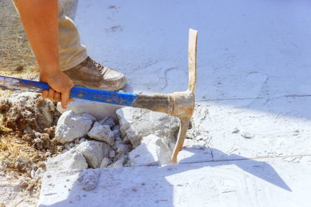 Téléchargez les photos : Démolition de l'allée en béton par un travailleur utilisant une pioche sur le chantier - en image libre de droit