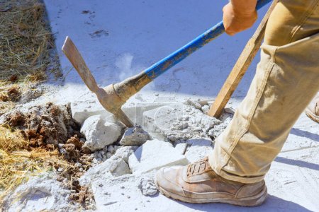 Photo for Worker smashes concrete old driveway with pickaxe on construction site - Royalty Free Image