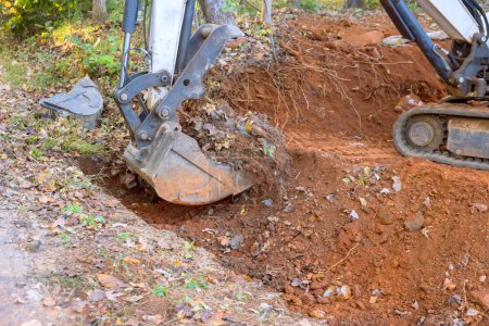 Téléchargez les photos : Travailleur utiliser tracteur creuse fossé pour la pose de drainage tuyau d'eaux usées en béton - en image libre de droit