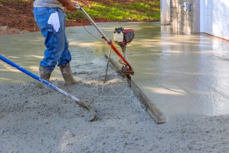 Photo for Utilizing tamping machine to align compacted concrete on new driveways - Royalty Free Image