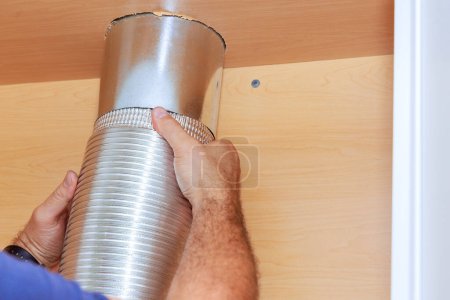 Téléchargez les photos : Installation travailleur plaçant tube pour hotte de cuisine sur l'armoire de cuisine - en image libre de droit