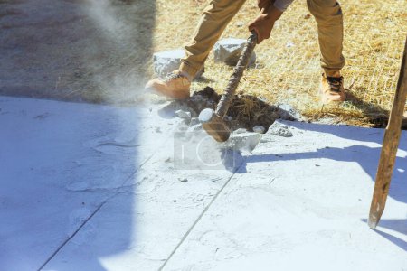 Téléchargez les photos : Démolition d'une ancienne allée en béton par un travailleur à l'aide d'un marteau sur le chantier - en image libre de droit