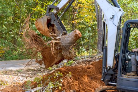 Téléchargez les photos : Utilisation d'un tracteur à barre dérapante pour enlever les racines et défricher les terrains pour la construction de logements complexes - en image libre de droit