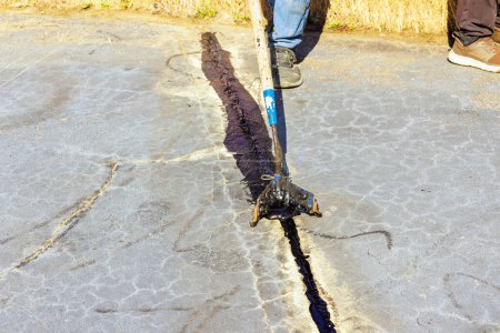Worker patcher performs coating, crack sealing, bitumen emulsion road surface restoration during workday
