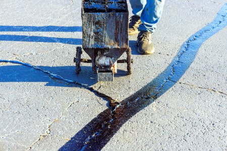 Foto de Un parche de asfalto realiza relleno recubierto grietas de asfalto sellado de emulsión de betún restauración de la superficie de la carretera - Imagen libre de derechos