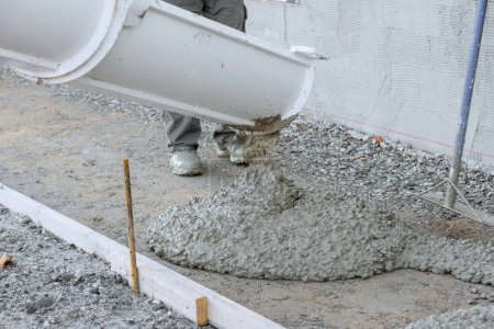 Arbeiter schütteten nassen Zement mit Betonmischwagen für neue Hauseinfahrt