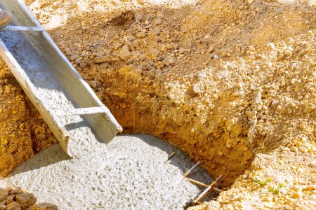 Téléchargez les photos : Travailleur de fondation coulant du béton ciment prêt à l'emploi pour la construction sur chantier - en image libre de droit