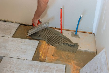 Photo for Preparation for laying tile on concrete floor by troweling adhesive onto it. - Royalty Free Image