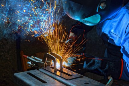 Photo for As worker welds steel with gas argon, sparks are generated that smoke inside factory - Royalty Free Image