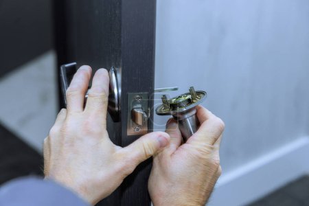 Téléchargez les photos : Mécanicien installe des poignées de serrure sur les portes de la chambre à la maison neuve - en image libre de droit