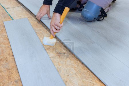 Photo for In newly constructed house worker is installing vinyl laminate flooring - Royalty Free Image