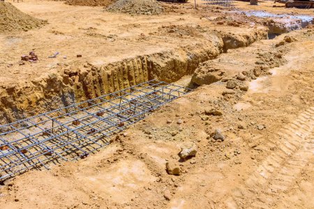 Photo for For purpose of pouring concrete deep strip foundation for trench is prepared - Royalty Free Image
