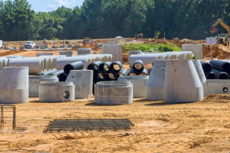 Téléchargez les photos : Le chantier de construction est préparé pour l'installation de tuyaux de drainage en béton empilé, tuyaux d'égout de trou d'homme, tuyaux d'eaux pluviales - en image libre de droit