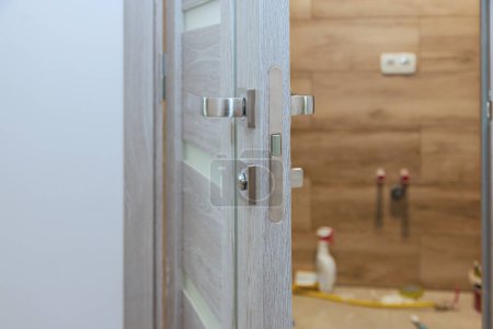 Téléchargez les photos : Poignées de serrure installées Handyman à la porte en bois - en image libre de droit