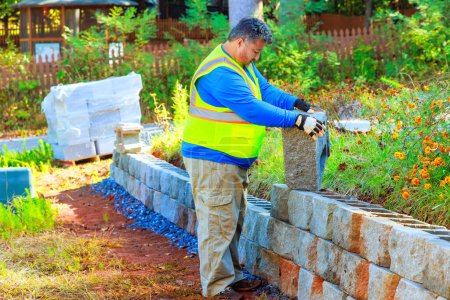 Foto de En obra de construcción trabajador de la construcción instala bloques de hormigón para muro de contención - Imagen libre de derechos