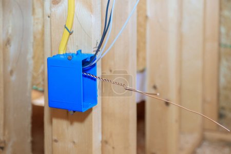 Photo for Plastic electrical switch box with wires at wooden frame beams on wall - Royalty Free Image