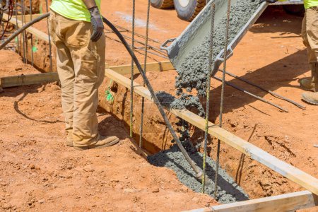 Photo for Concrete vibrator being used by construction worker in order to compact concrete into trenches for foundation of house - Royalty Free Image