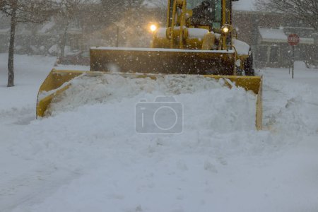During heavy snowfall, snow is removed from parking lot by snowplow truck