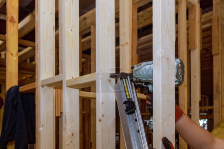 Téléchargez les photos : Builder utilise un marteau pneumatique pour fixer des poutres en bois pour loger le cadre - en image libre de droit