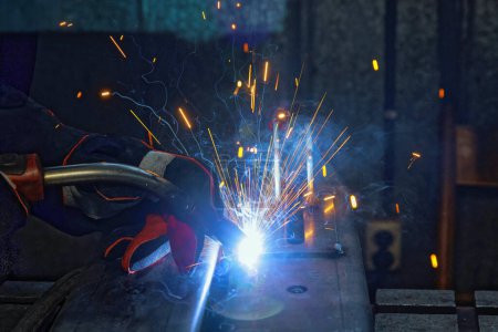 Photo for In factory, sparks are created as workers weld with gas argon to steel - Royalty Free Image