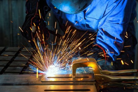 Photo for When workers weld using gas argon to steel, sparks are created that result in smoke within factory - Royalty Free Image