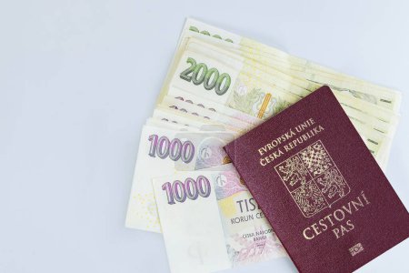 Pasaporte República Checa se apilan junto con billetes varias denominaciones de coronas checas apiladas sobre fondo blanco