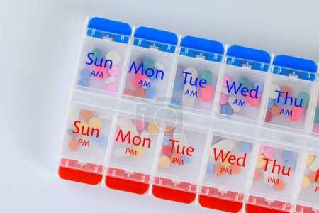 Organizador diaria caja dispensador de pastillas con cápsulas de medicamentos sobre fondo aislado blanco.
