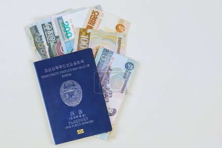 Foto de Moneda ganó moneda norcoreana en billetes en efectivo de pasaportes norcoreanos sobre fondo blanco - Imagen libre de derechos