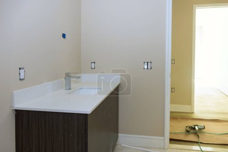 En el cuarto de baño, instalación de lavabos, gabinete con cajones, fregadero de porcelana blanca con grifo de acero inoxidable