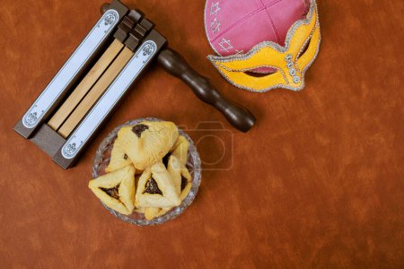 Téléchargez les photos : Masque de carnaval, biscuits hamantaschen, bruyants, ont été utilisés pour célébrer la fête juive de Pourim - en image libre de droit