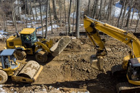 Construction excavator digs trenches at construction site during earthmoving operations to prepare infrastructure