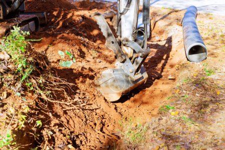Photo for Through trench dug by an excavator, pipe will be laid to convey rainwater to collection system - Royalty Free Image