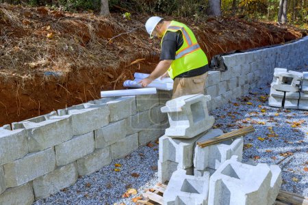 Bauarbeiter verwenden typischerweise Baupläne, wenn sie Betonblöcke als Stützmauern montieren