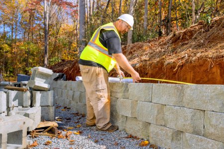 Téléchargez les photos : Au cours du montage des murs de soutènement par blocs de ciment, les travailleurs de la construction ont étudié les plans - en image libre de droit