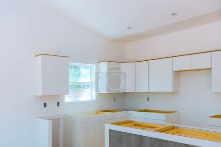 Kitchen cabinets made of wood white are being installed in newly constructed house
