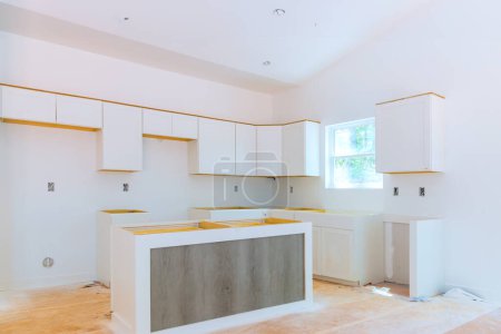 Newly constructed house is being fitted with wooden white kitchen cabinets