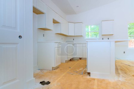 In newly constructed house, wooden white kitchen cabinets are being installed