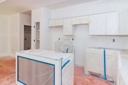 An installation white wooden kitchen cabinets is taking place in newly constructed kitchen new home