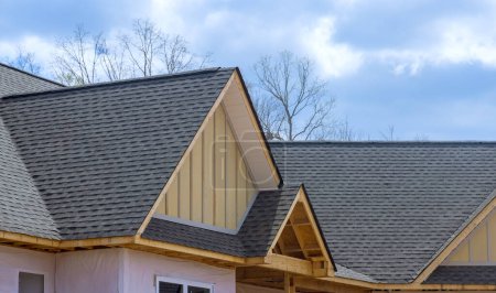 Foto de En la casa de nueva construcción, se ven tejas de asfalto superpuestas en el techo - Imagen libre de derechos