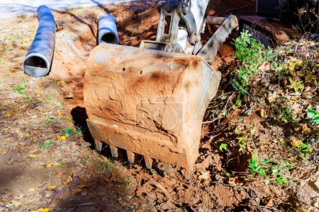Photo for An excavator digs trench for laying pipe through which rainwater will flow to collector - Royalty Free Image