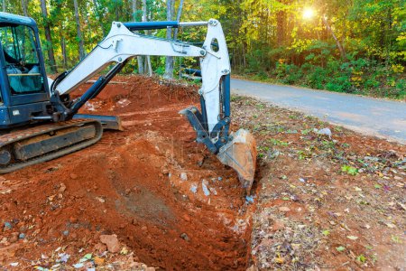 Photo for During construction of collection system, an excavator digs trench in which pipe will be laid for flow of rainwater - Royalty Free Image