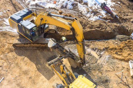 During earthmoving works on construction site, an excavator digs trenches