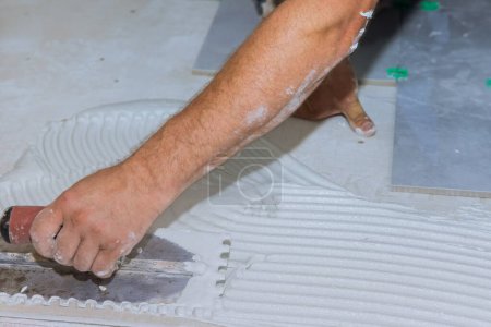 During installing ceramic tiles on concrete floor with adhesive mortar cement plaster