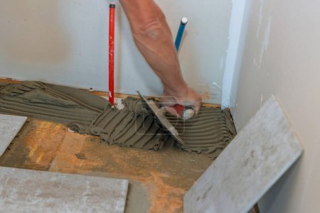 Photo for Applying adhesive to concrete floor prior to laying tile. - Royalty Free Image