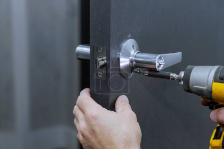 Téléchargez les photos : Installation de poignées de serrure sur les portes de la pièce avec tournevis par charpentier - en image libre de droit