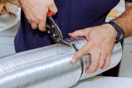 Un individu coupe flexible tuyau ondulé en aluminium afin de le connecter au système de ventilation