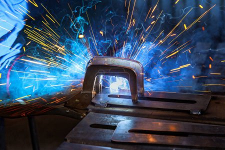 Photo for Worker welding steel with gas argon creates sparks that can cause smoke in workplace - Royalty Free Image