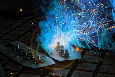 As worker welding using gas argon to steel light sparks are created that smoke in factory at work
