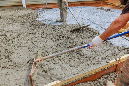 Bauarbeiter ebnen Beton mit speziellen Werkzeugen