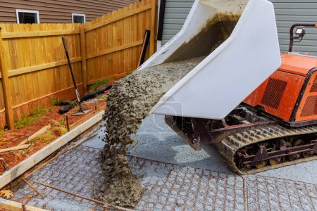 Téléchargez les photos : Le ciment humide est versé dans le cadre à l'aide d'un chariot à béton auto-vidangeur pendant la construction de fondations - en image libre de droit